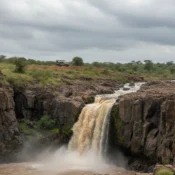 Wide view of Makalia Falls Lake Nakuru with a safari 4x4 parked in the distance.