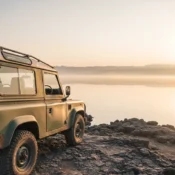 A vintage safari 4x4 vehicle parked on the rocky shore of Lake Nakuru in 2026.