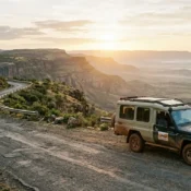 A safari vehicle parked on the winding Mai Mahiu escarpment road overlooking the Great Rift Valley.