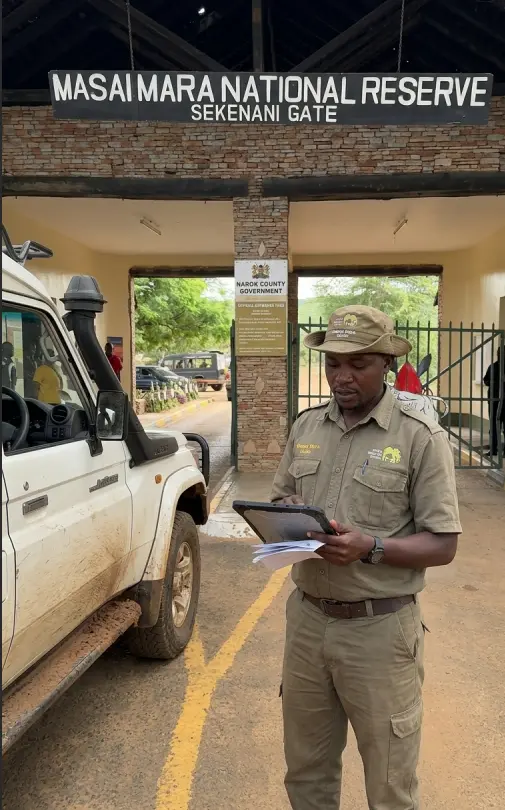 A safari guide coordinating park entry at a Masai Mara National Reserve gate.