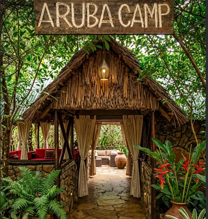 Authentic stone and thatch entrance pathway to the Aruba Mara Camp reception area, surrounded by dense indigenous ferns and tropical flowers.