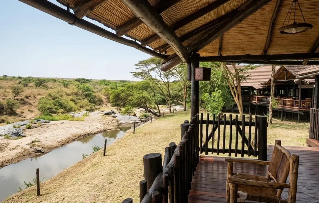 View from a wooden veranda at Mara Simba Lodge looking over the Talek River bank and surrounding savanna trees.