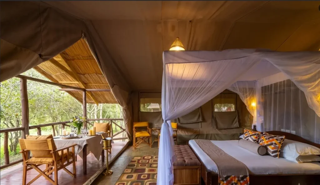 Interior view of a deluxe safari tent at Sentrim Mara Lodge with a mosquito-netted bed and an attached wooden private dining veranda.